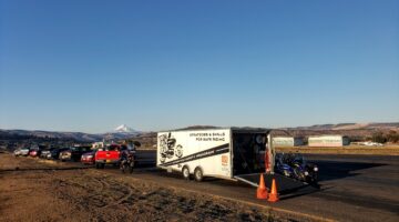 Open Team Oregon trailer with parked motorcycles and orange cones