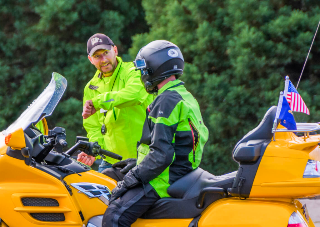 Instructor talking with student on yellow motorcyle